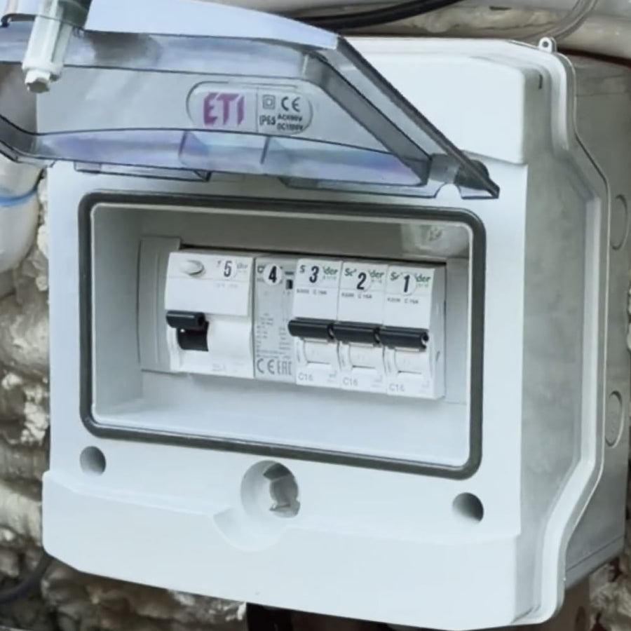 A white electrical box with switches and a leakage relay, located inside the side wall of the hot tub