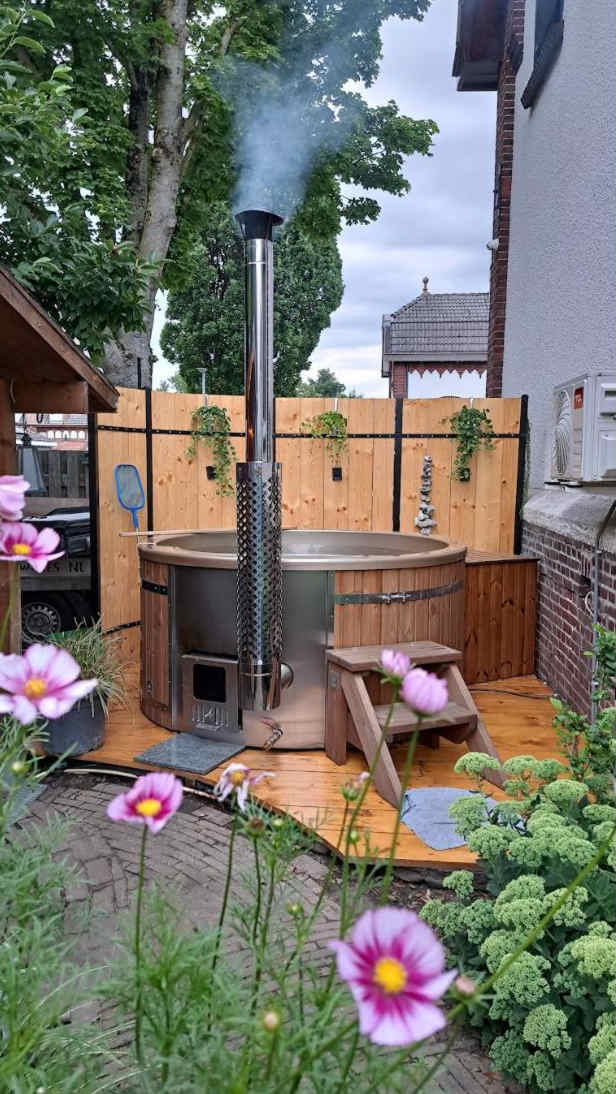 Gardenvity wood fired hot tub in a cozy courtyard garden with flowers and privacy fence.